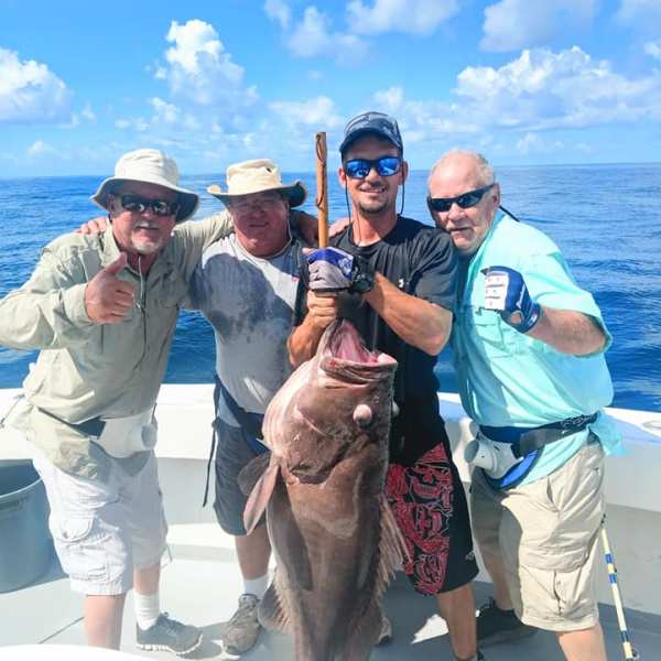a group of people standing next to a person holding a fish