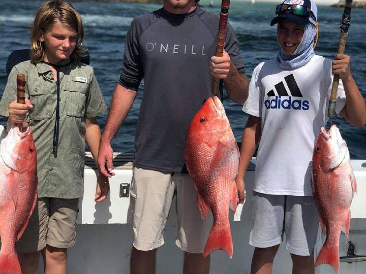 a group of people standing next to a man holding a fish